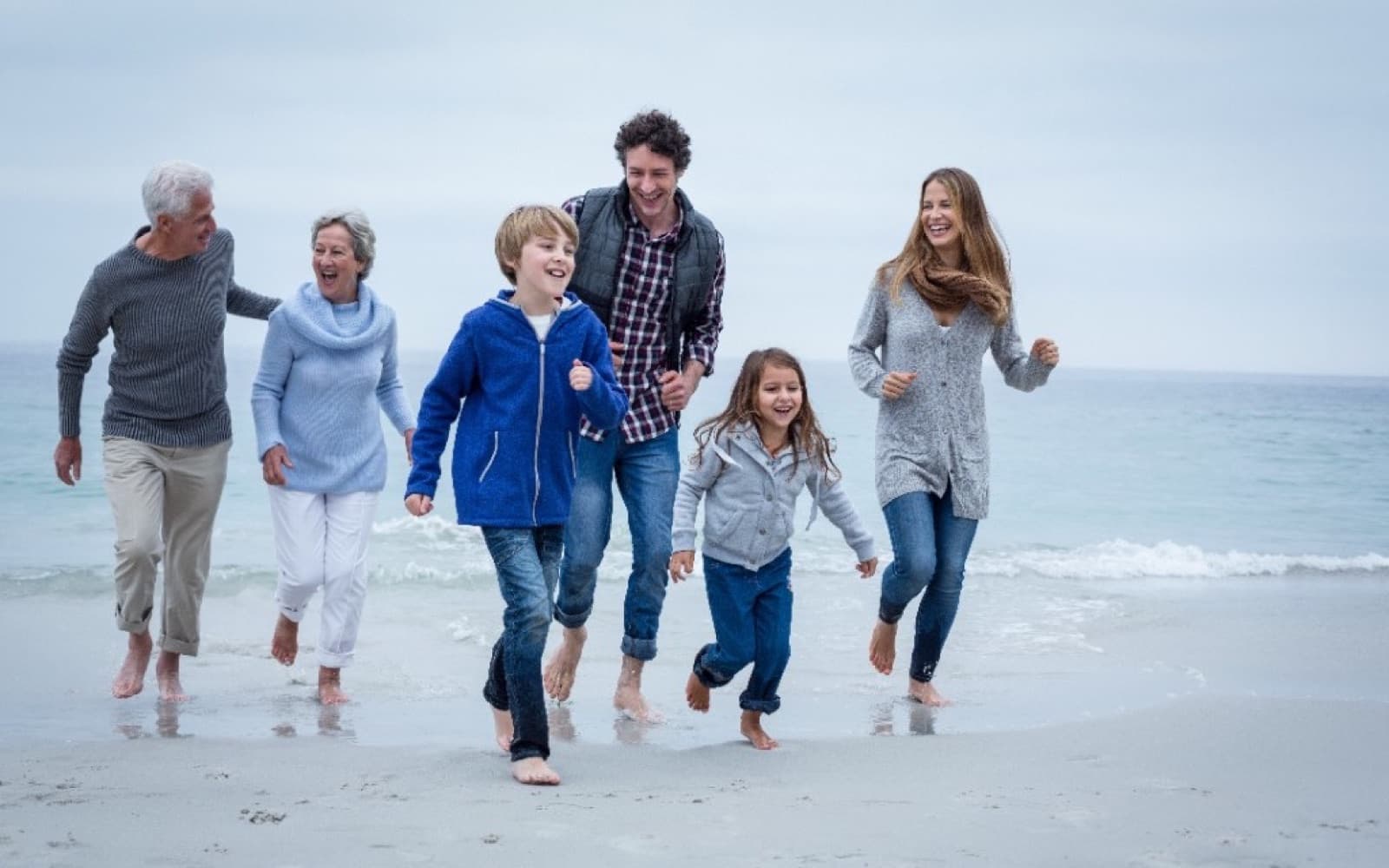 Three generations running together along a beach.